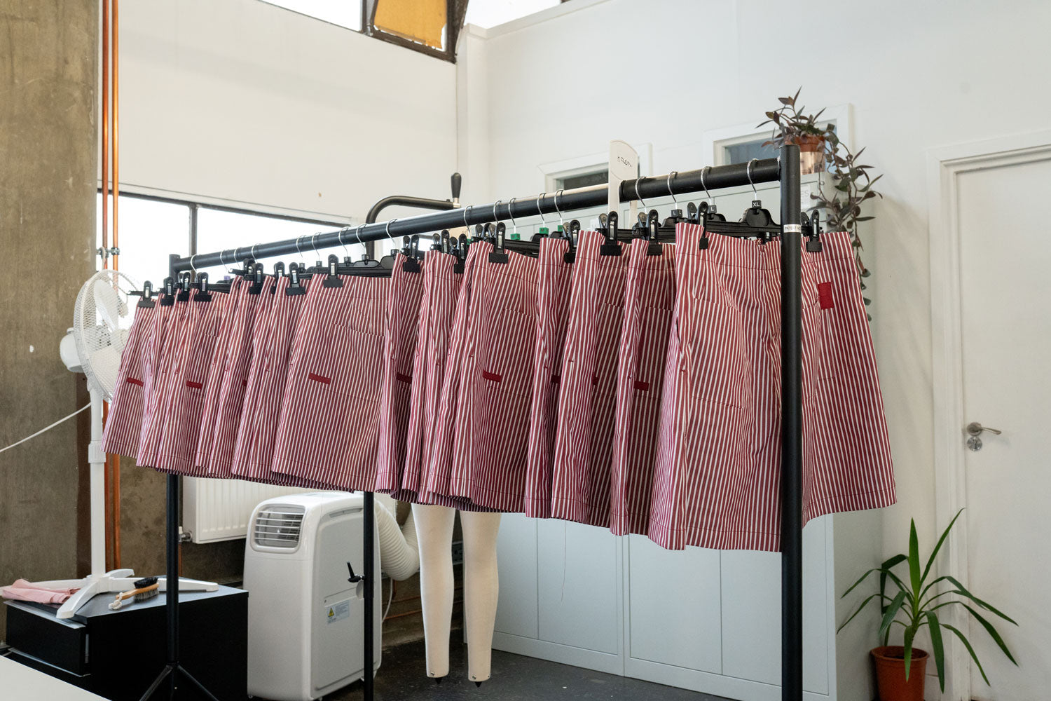 Saywood's Bessie Aline Shorts in Berry Red Stripe production can be seen hanging on a rail in MAES, the London factory. Handmade in the UK