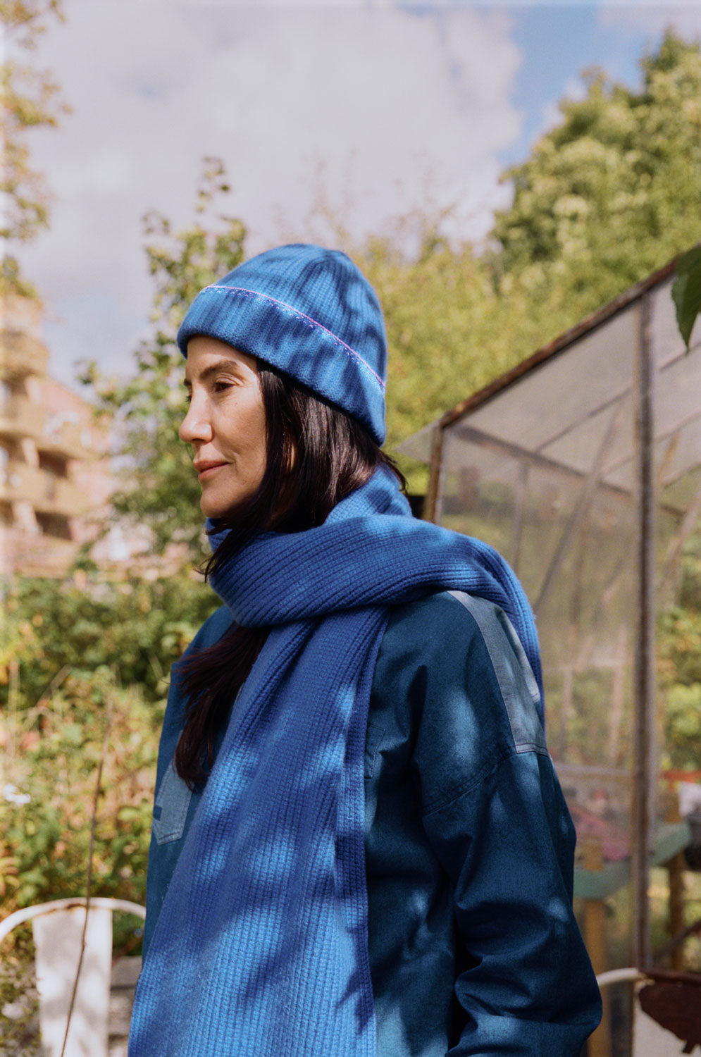 Model wearing blue beanie hat outdoors, showing pink crochet trim and cosy winter styling