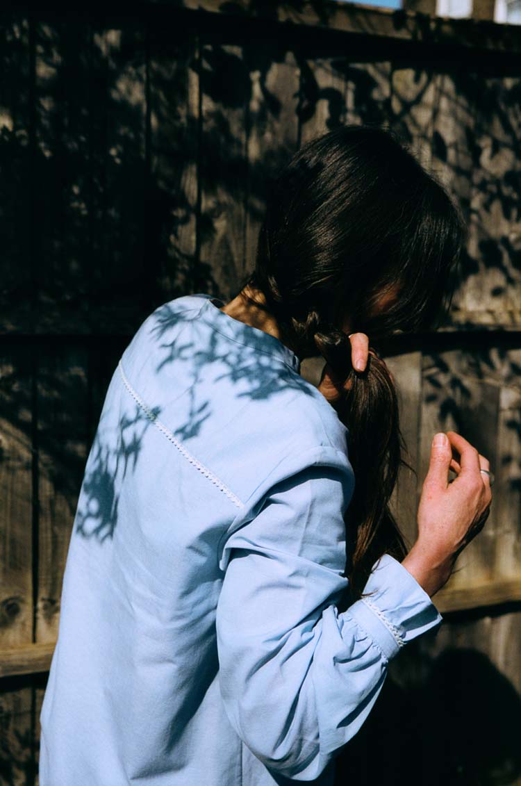 Marie Blouse in pale blue recycled cotton, dappled in sunlight — last chance sustainable womenswear by Saywood, made in England