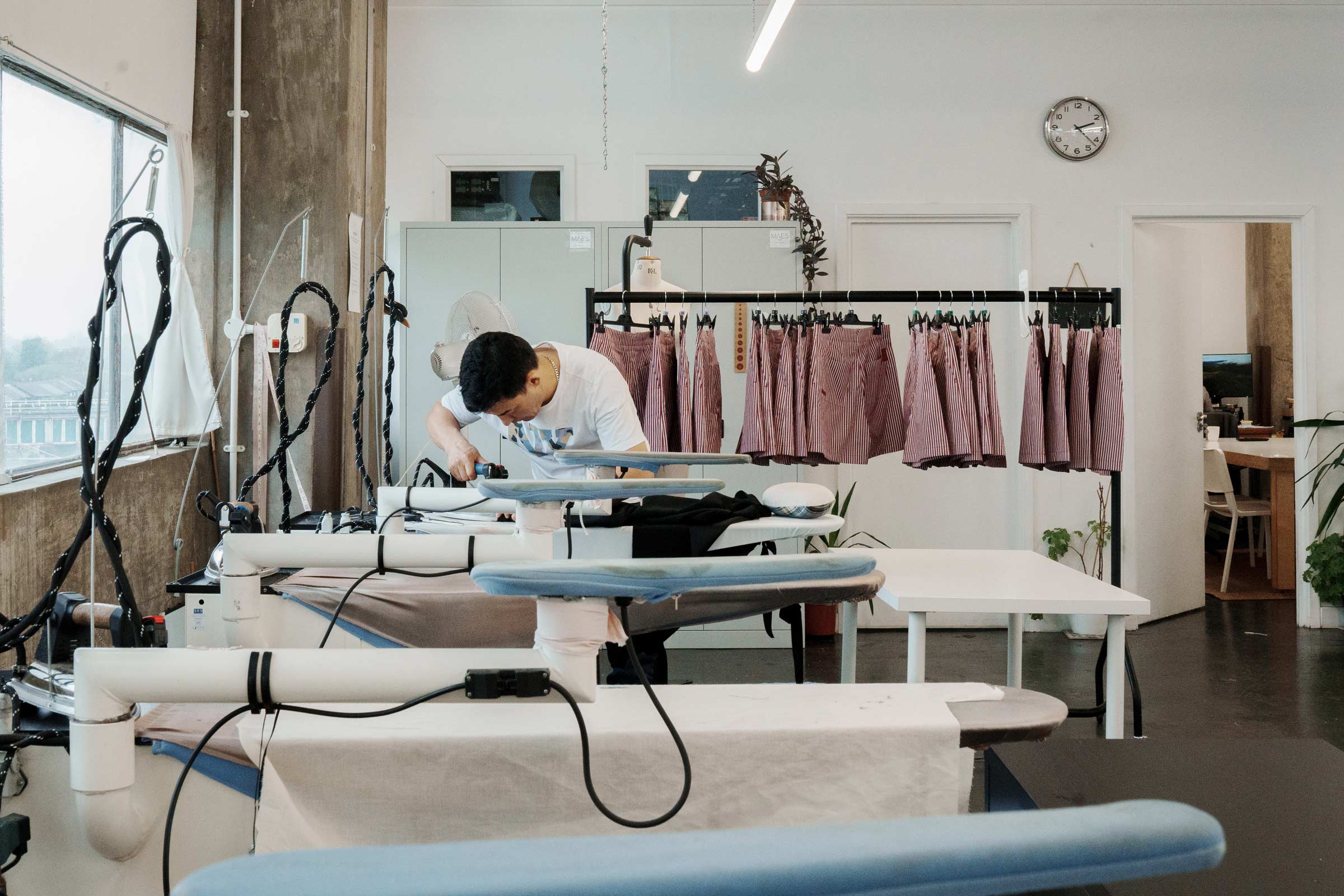 A garment maker pressing and finishing clothing at a London production studio — sustainable fashion made in the UK by Saywood