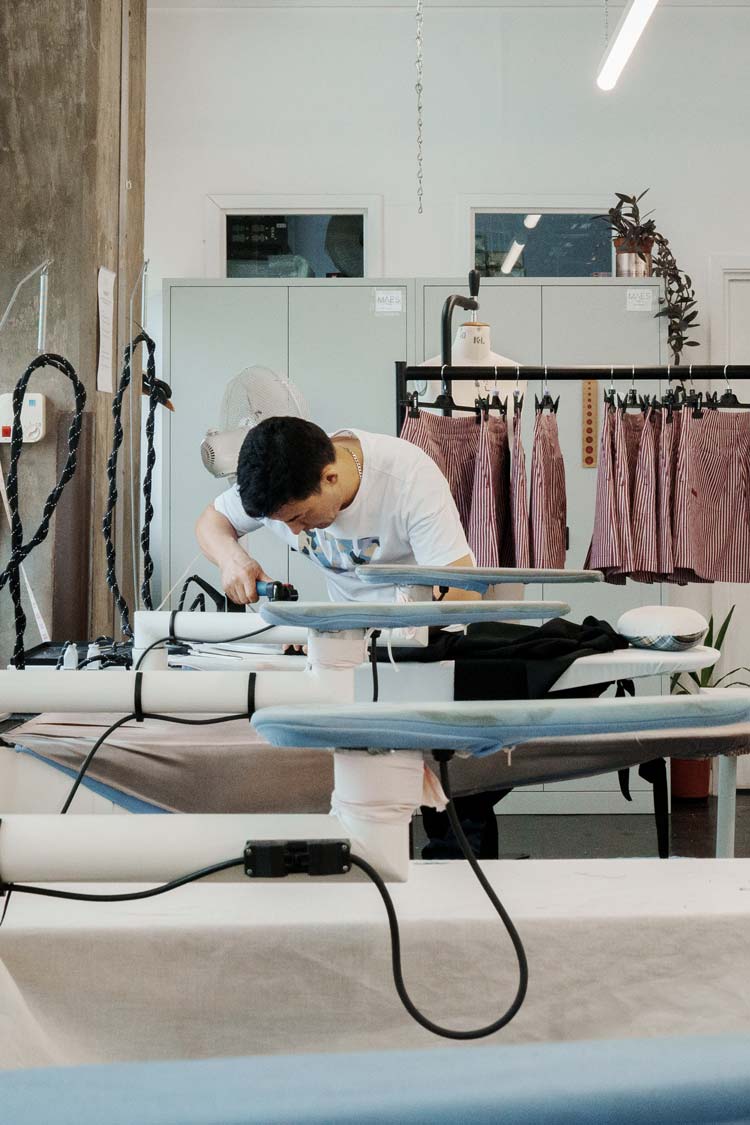 A garment maker pressing and finishing clothing at a London production studio — sustainable fashion made in the UK by Saywood
