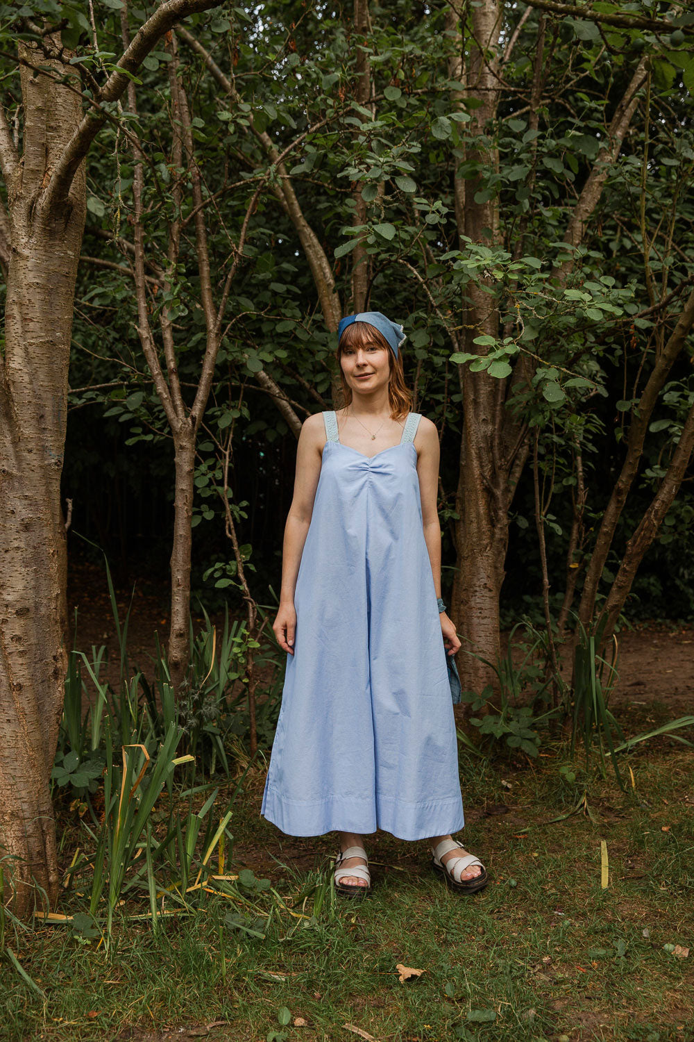 Maya Cami Dress in pale blue recycled cotton, worn without belt, full length model in a woodland setting. By Saywood. Made in London.