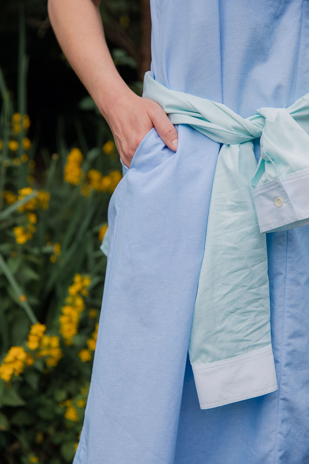 Maya Cami Dress in pale blue recycled cotton, styled with Lela Shirt in green blue tied around waist. By Saywood. Made in London.