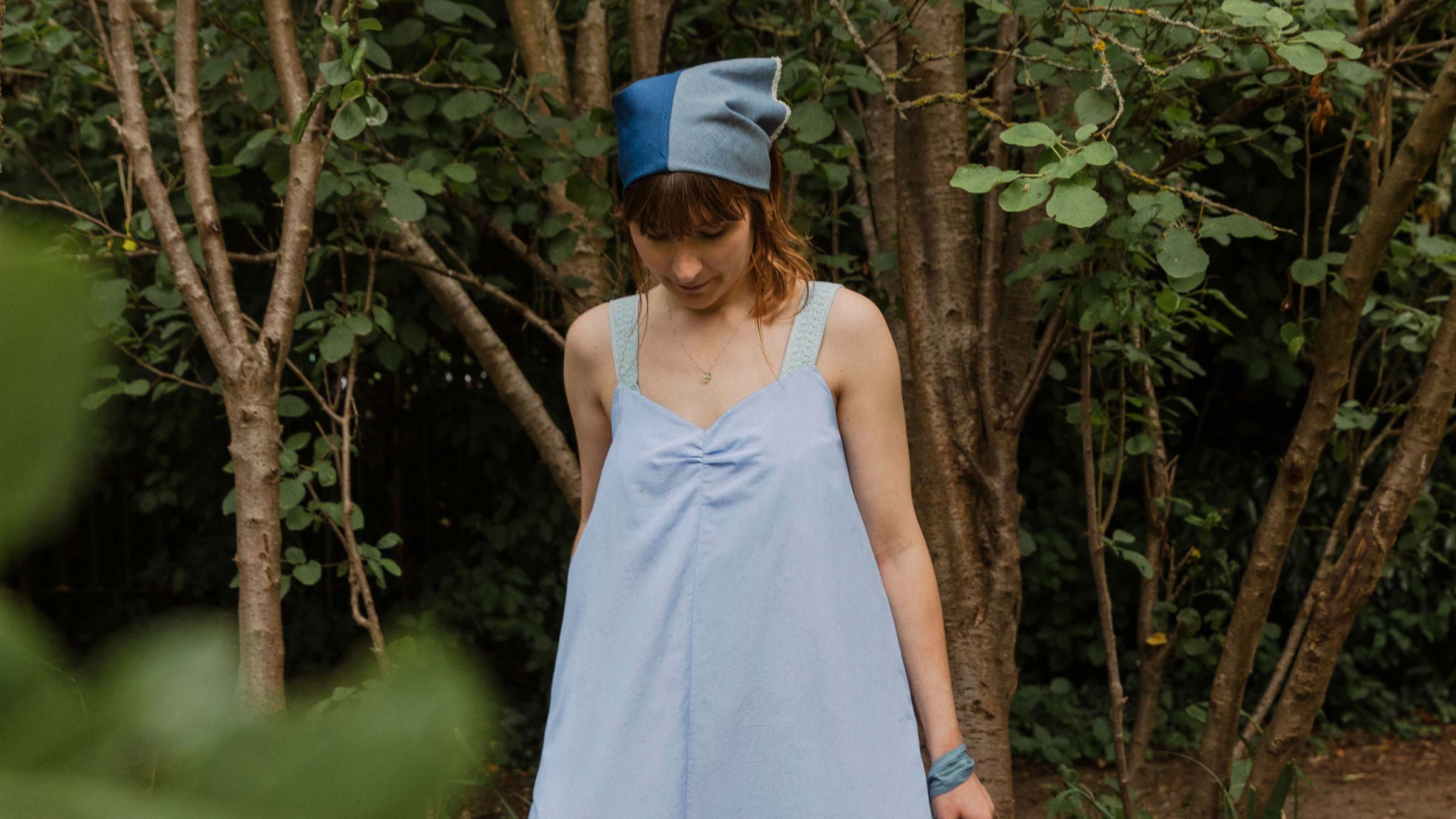 Maya Cami Dress in pale blue recycled cotton, worn in a woodland setting — made in London by Saywood