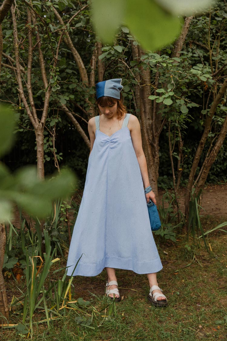 Maya Cami Dress in pale blue recycled cotton, worn in a woodland setting — made in London by Saywood