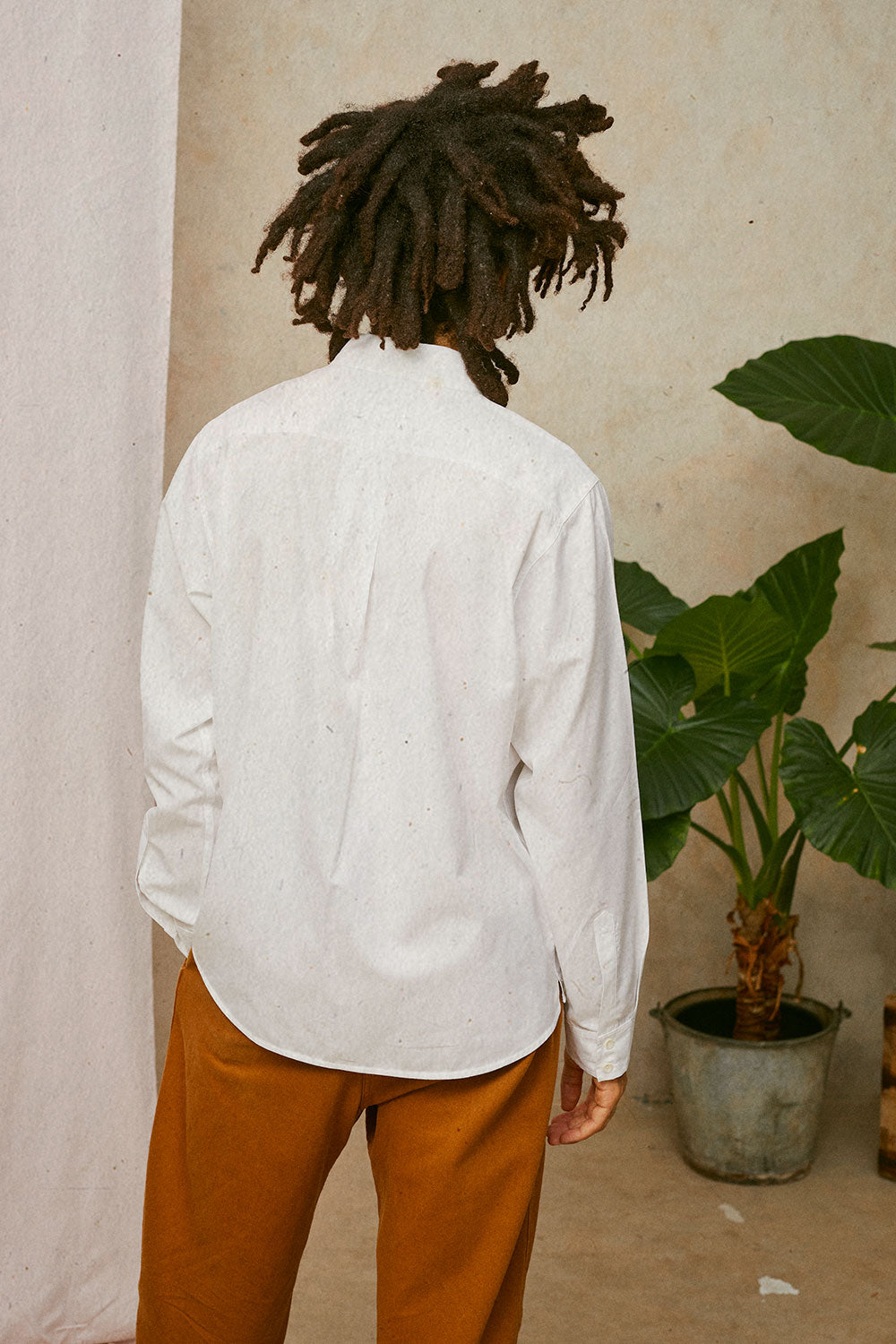 Back detail of Eddy men's white patch pocket shirt showing back yoke and box pleat, made in London by Saywood. Worn with tobacco trousers.