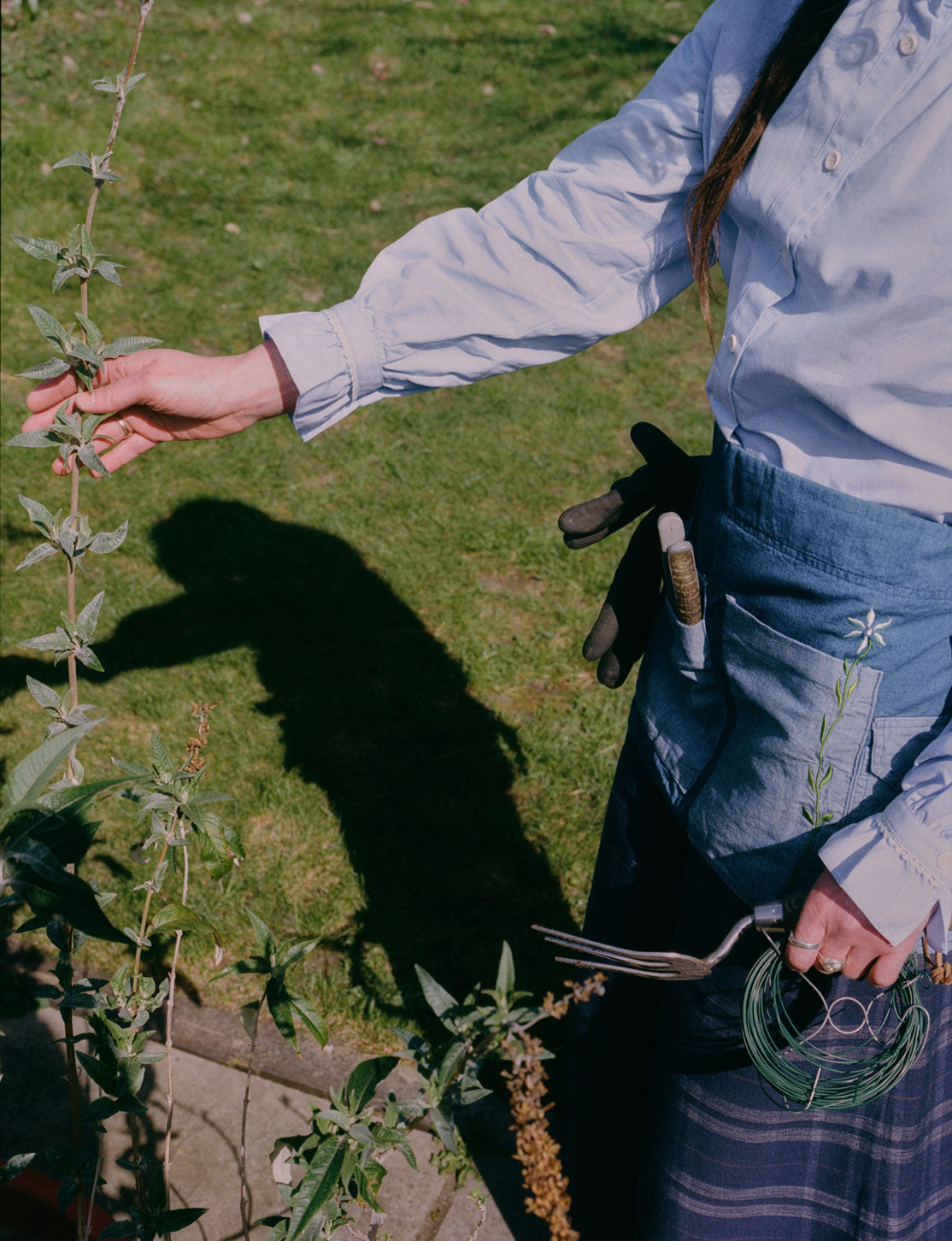 Japanese denim gardener's apron in use with garden tools, styled with Marie blouse and Amelia trousers by Saywood