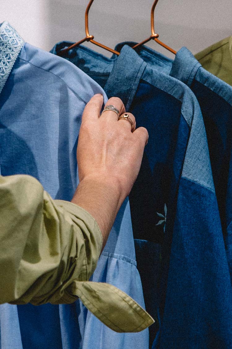 Browsing a rail of natural fibre shirts in blue and olive — sustainable materials used by Saywood