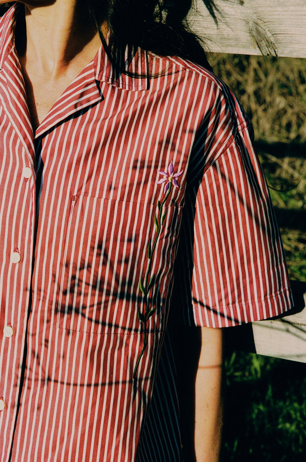 Close-up detail of Frances Cuban shirt embroidered flower on chest pocket, berry red stripe surplus cotton by Saywood