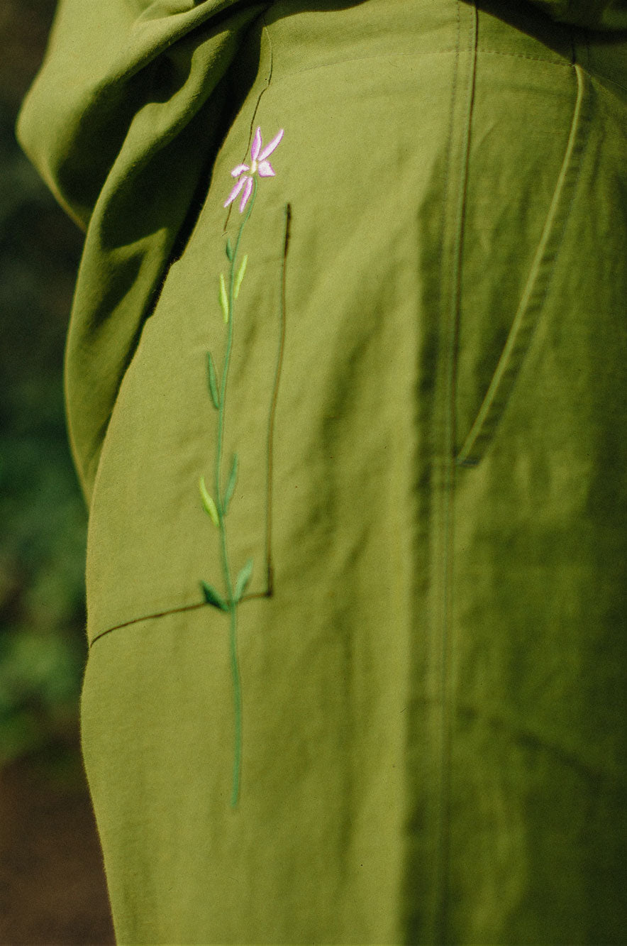 Close-up detail of Bessie shorts back pocket with signature embroidered flower in rich olive green by Saywood