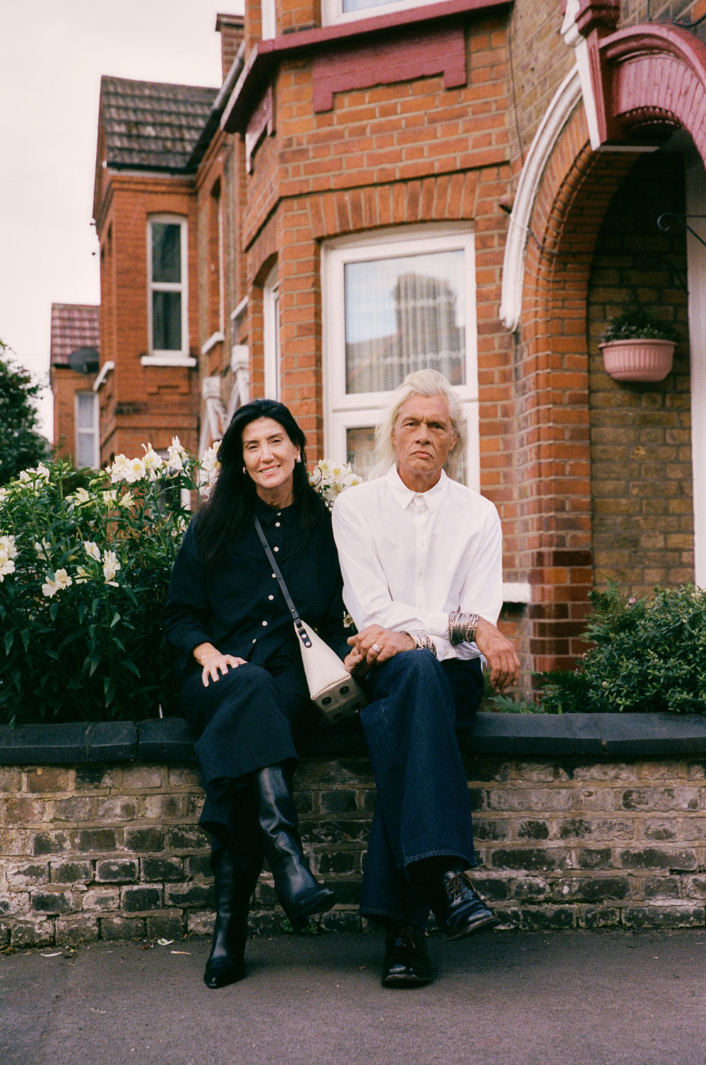 Woman wears Lela black Japanese denim shirt with Amelia black trousers, man wears Eddy classic white shirt in cotton bamboo, made in London by Saywood