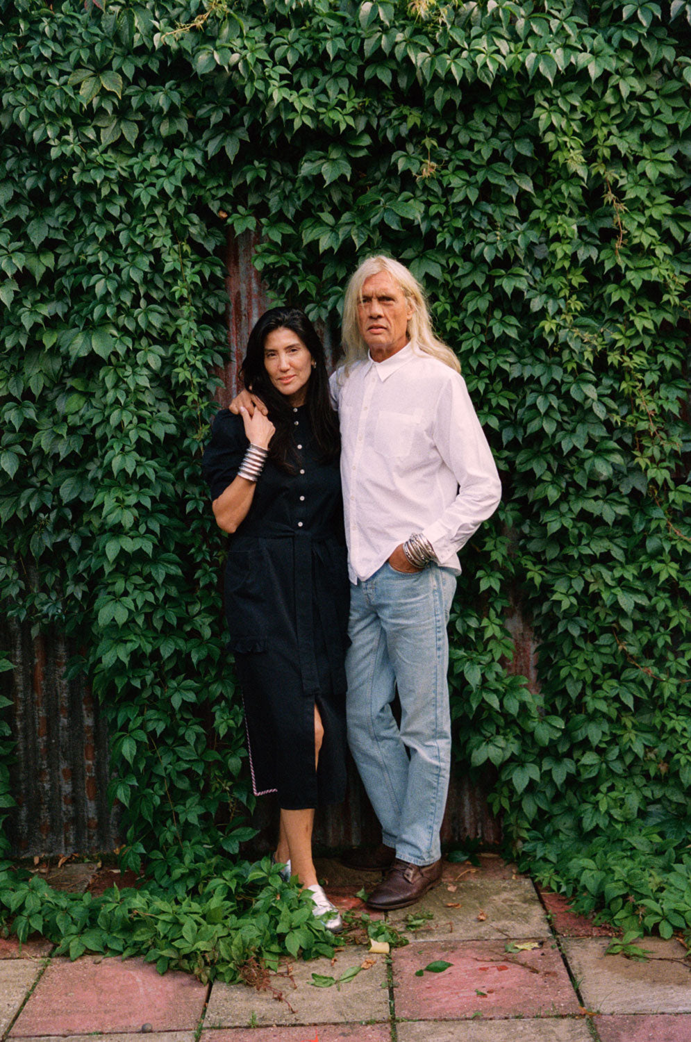 Woman wears Rosa black Japanese denim shirtdress with Eddy men's white patch pocket shirt in cotton bamboo, handmade in London by Saywood