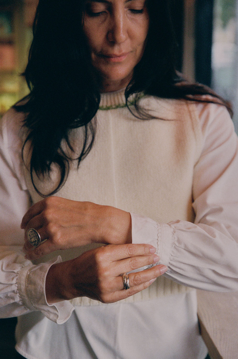 Model wearing cream lambswool Ada Sweater Vest over white Marie Blouse. Boxy fit knitted tank with textured half-purl, half-jersey stitch, made in the UK by Saywood.