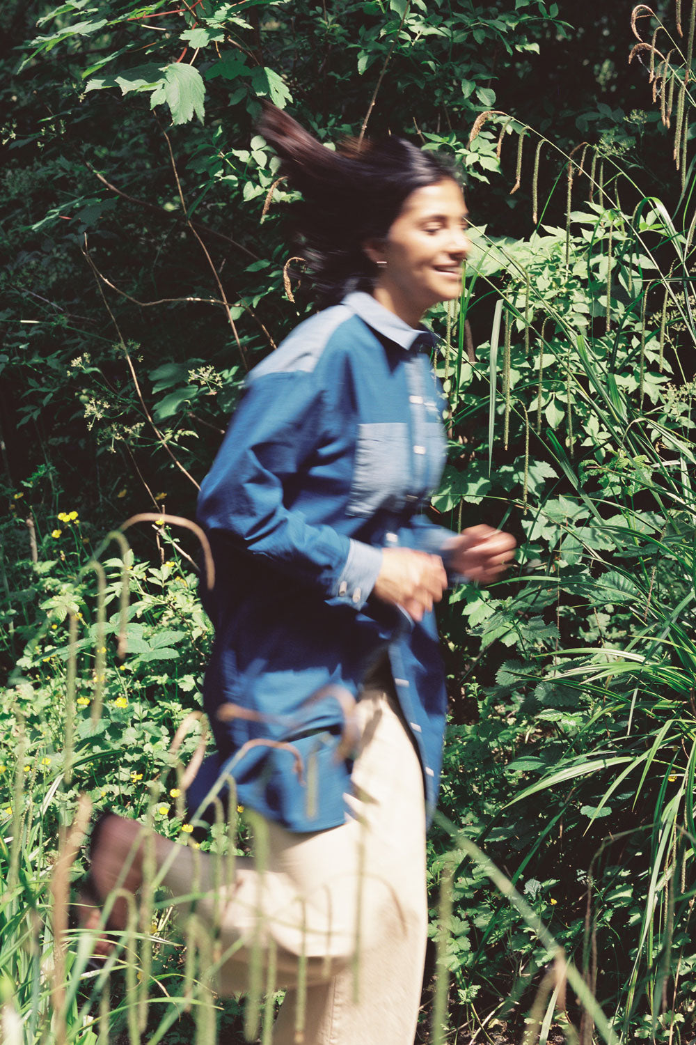 Woman in Etta oversized Japanese denim shirtdress styled over tan trousers