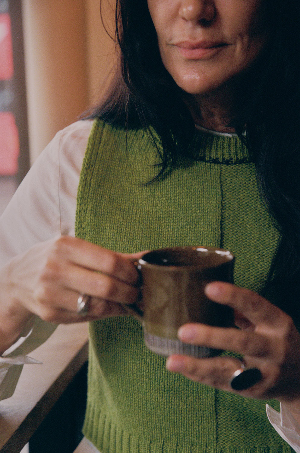Close-up detail of moss green Ada Sweater Vest showing textured half-purl, half-jersey lambswool knit and midnight navy contrast stitching at neckline.