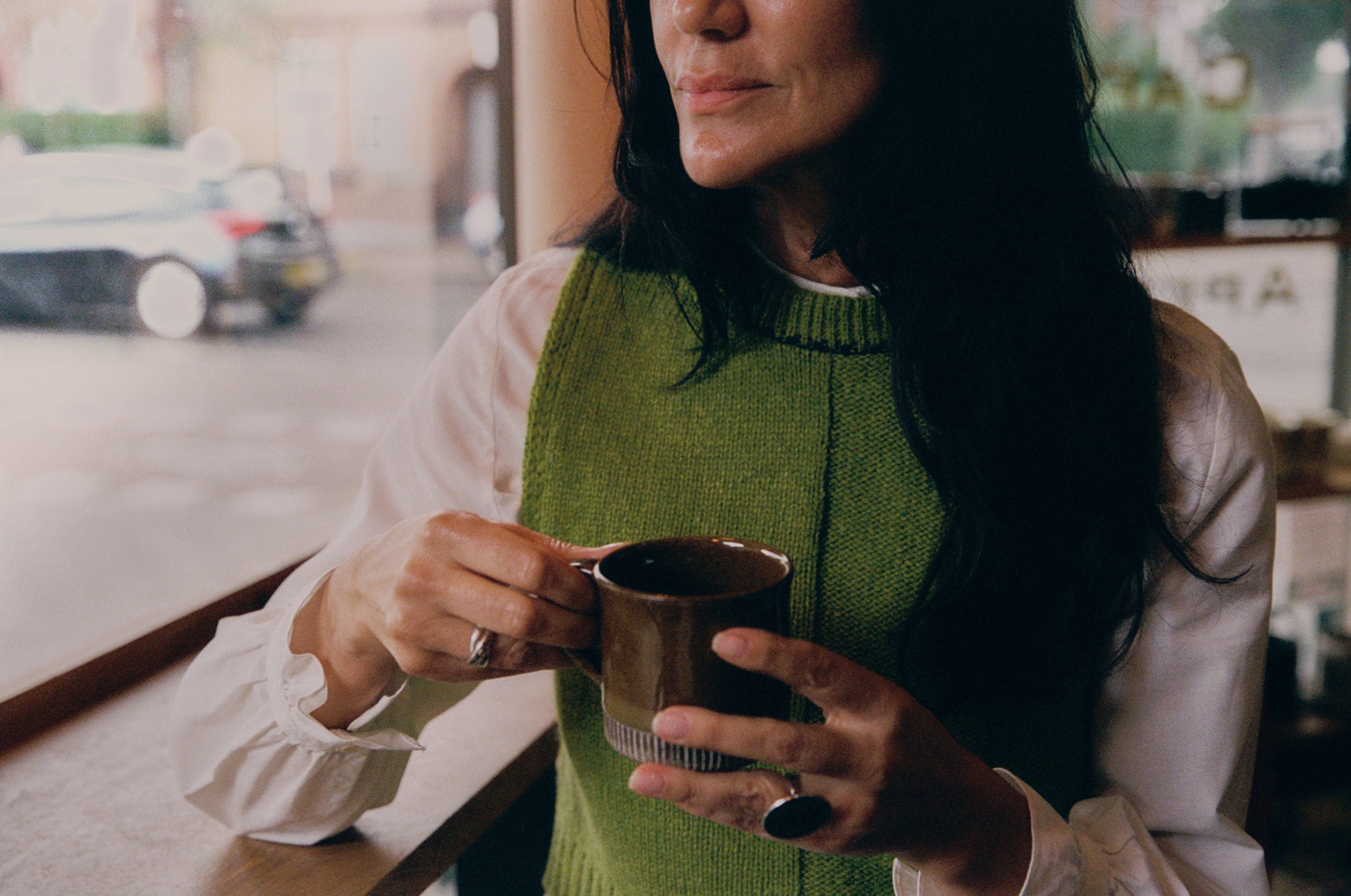 Model wearing moss green lambswool Ada Sweater Vest. Boxy fit knitted tank with textured half-purl, half-jersey stitch, made in the UK by Saywood.