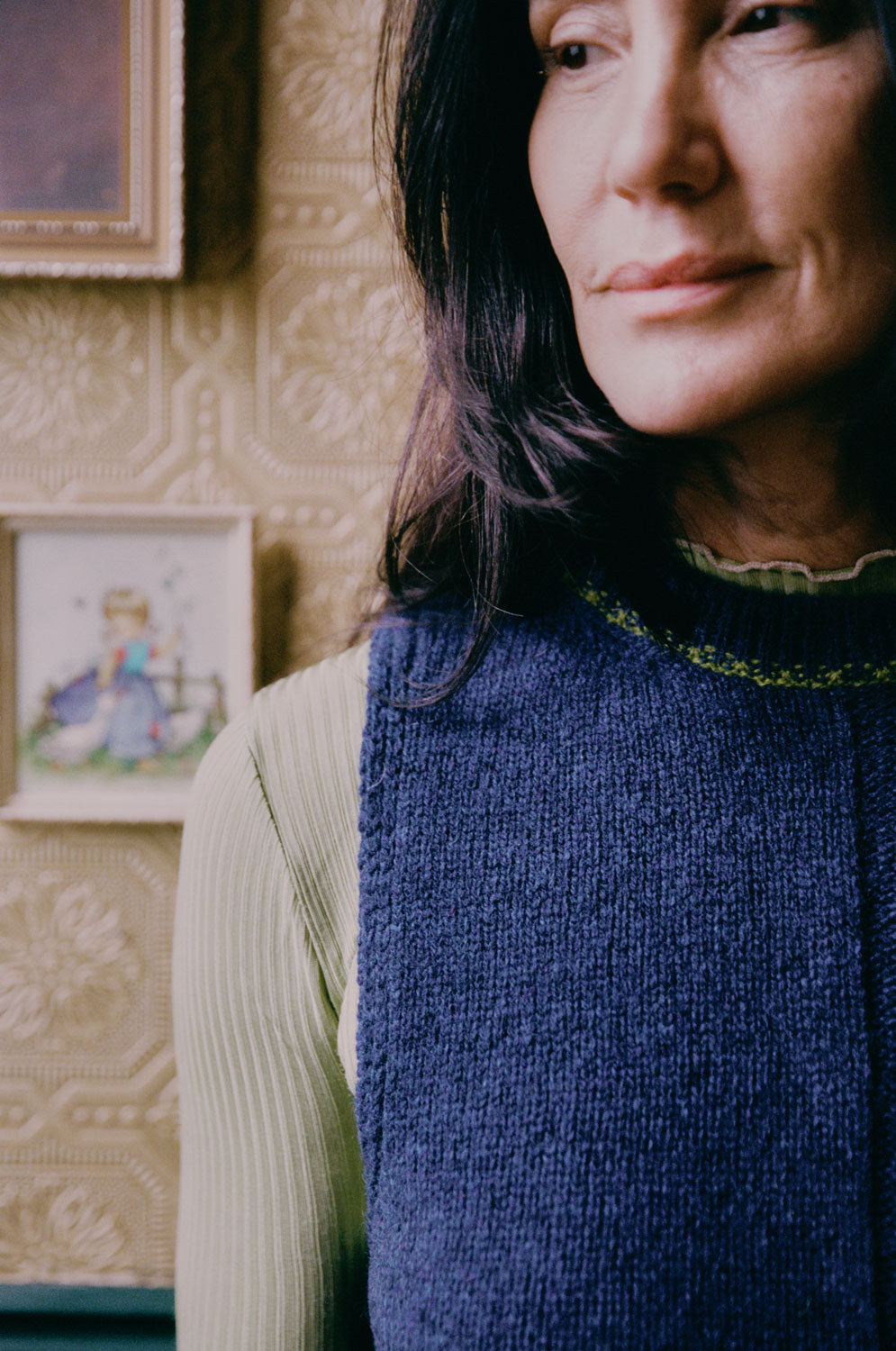 Close-up detail of midnight navy Ada Sweater Vest showing textured half-purl, half-jersey lambswool knit and moss green contrast stitching at neckline.