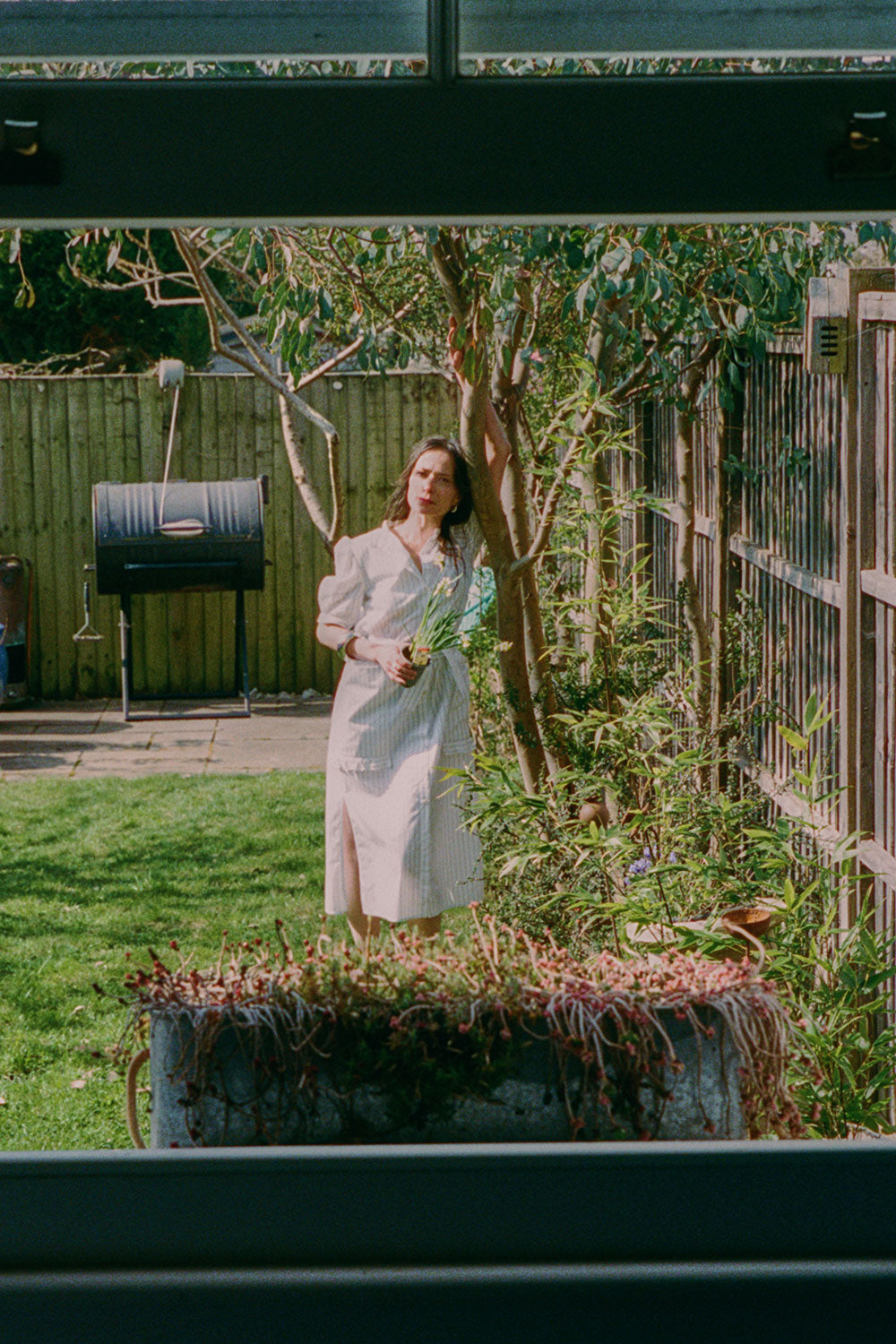 Lifestyle shot: Rosa white pinstripe shirtdress with detachable belt styled with black sandals by Saywood