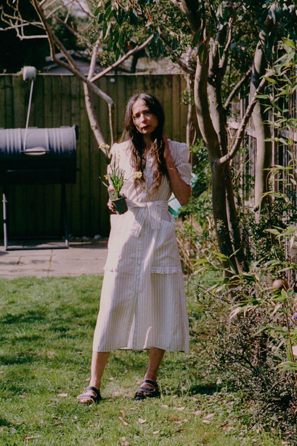 Lifestyle shot: Rosa puff sleeve shirtdress in white cotton pinstripe with ruffle pocket detail, made in London by Saywood