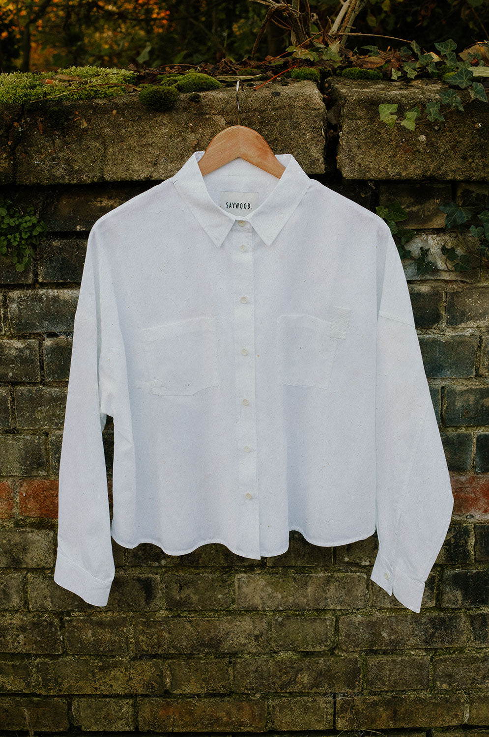 White recycled cotton Lela boxy shirt on hanger showing patch pockets and sustainable craftsmanship by Saywood