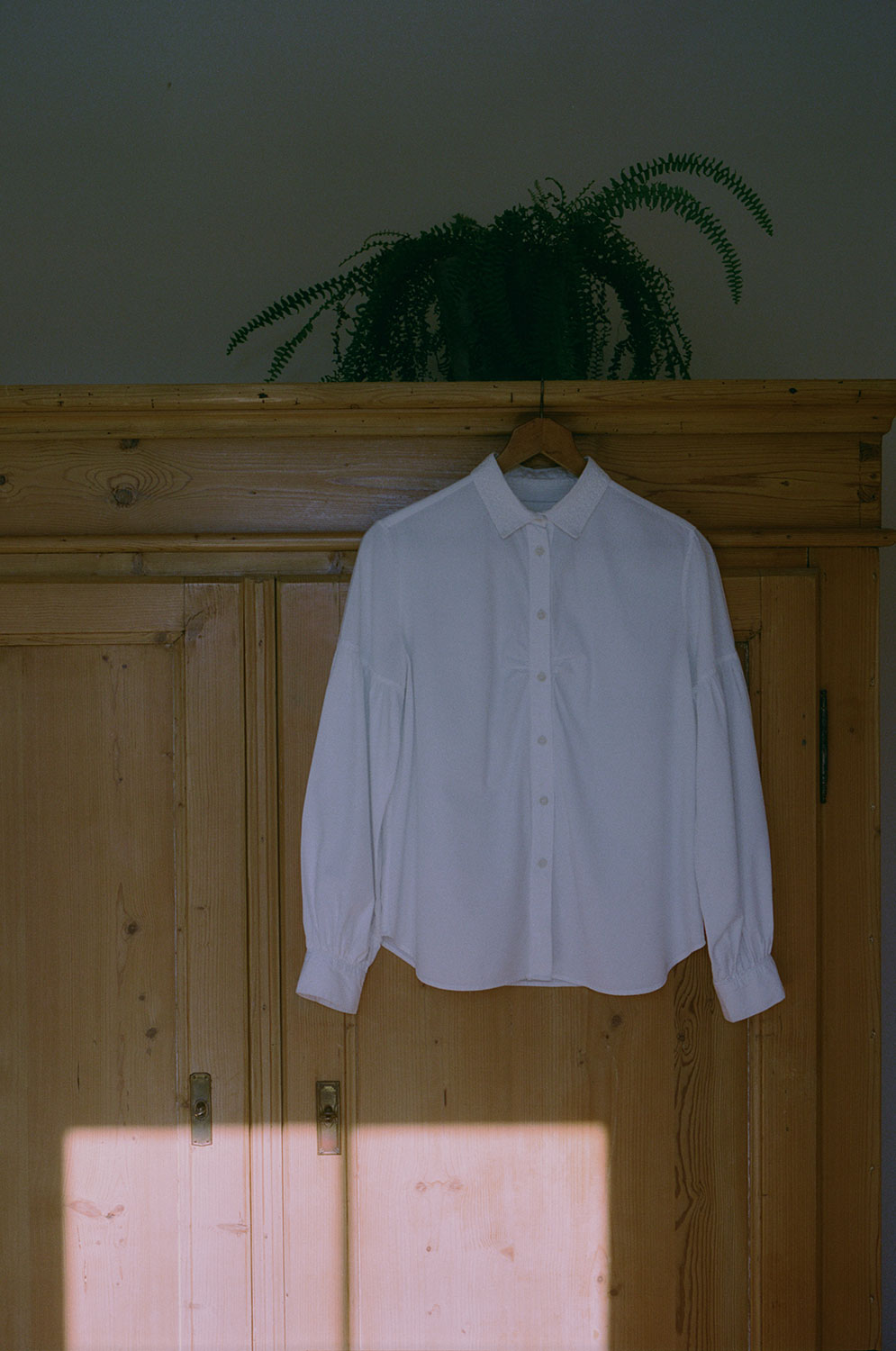 Edi white shirt with lace collar hanging on vintage wardrobe in natural light