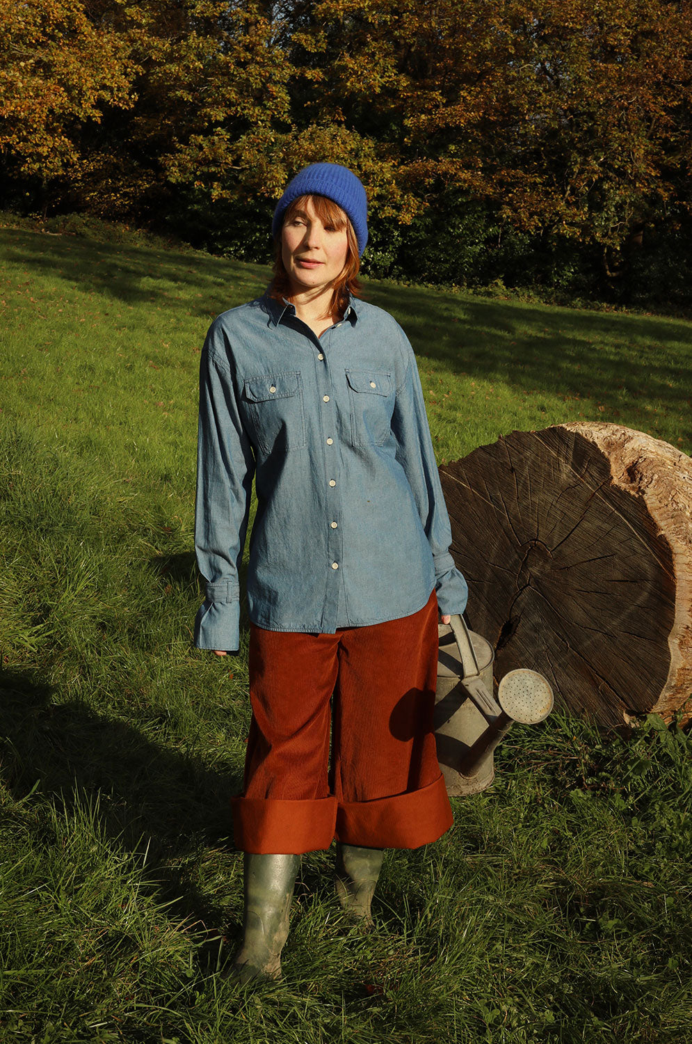Lifestyle shot: Amelia caramel corduroy trousers rolled up with wellies and Zadie Japanese denim shirt, made in London by Saywood